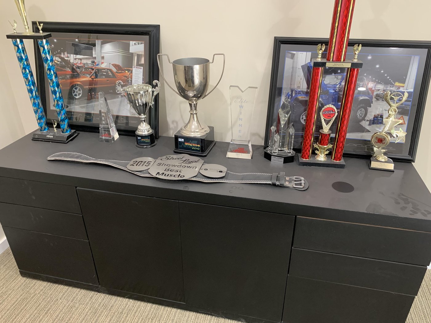 Blalock Customs award shelf with show trophies, a championship belt, and framed feature photos