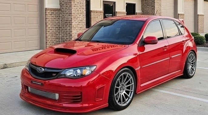 Red Subaru WRX STI parked outside the Blalock Customs collision repair shop